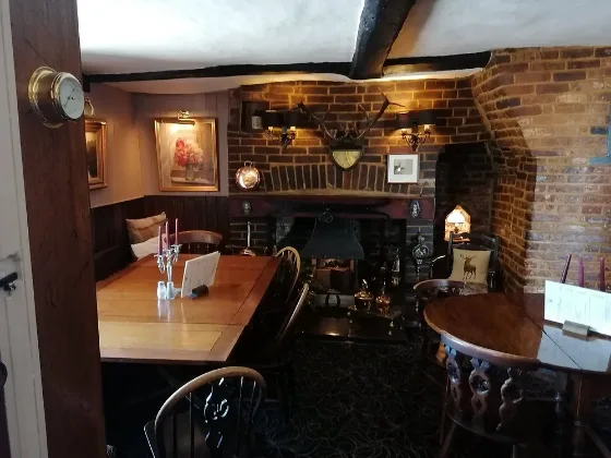 The dining room: exposed brick, a beamed ceiling, laid tables and pictures on the walls.