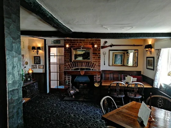 The snug at The Holly Bush, with dark panelling, a fireplace and framed pictures.